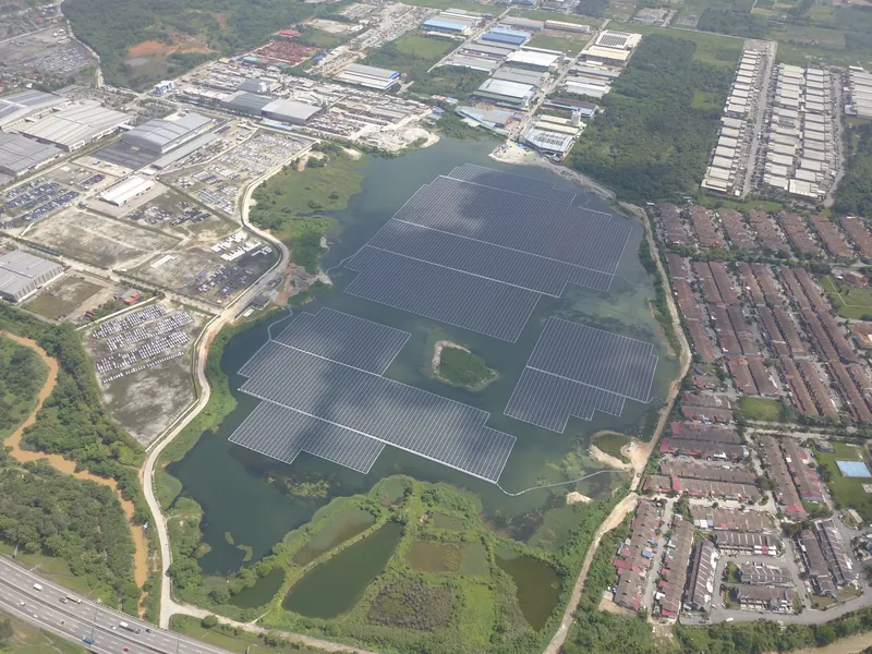 Aerial view of a floating solar array on a lake next to an industrial estate
