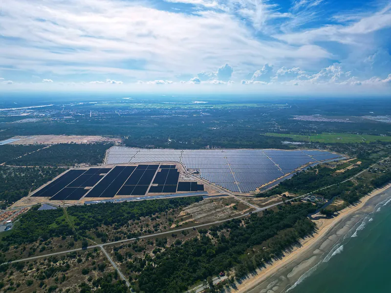 Aerial view of a large ground-mounted solar farm beside the sea